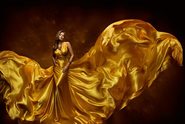 لباس طلای زنانه لباس زنانه در لباس طلایی ابریشمی مدل زیبایی مد پارچه بافته در باد دختر زیبا با پارچه بلند پرواز پویا