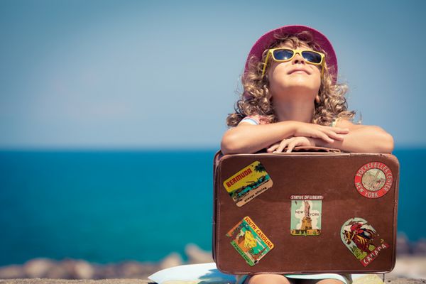 کودک با چمدان پرنعمت در تعطیلات تابستانی مفهوم سفر و ماجراجویی