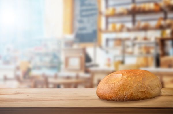 نان تازه خرد شده روی میز چوبی در فروشگاه نانوایی