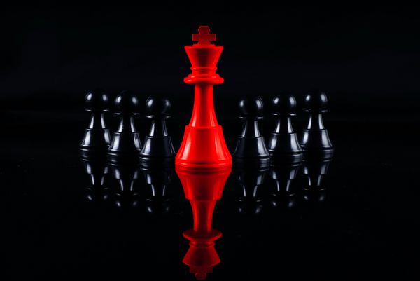 مفهوم رهبری شطرنج با شطرنج قرمز و سیاه و سفید جدا شده در پس زمینه سیاه و سفید