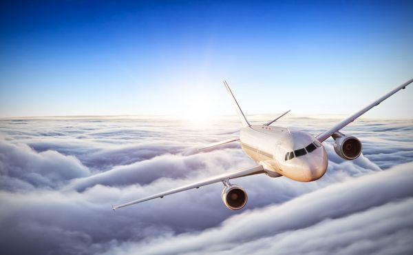 هواپیما تجاری پرواز در ابرهای بالاتر در نور غروب آفتاب وضوح تصویر بسیار بالا