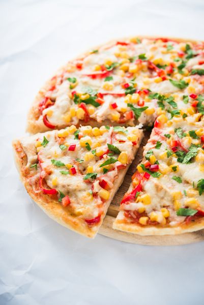 پیتزا برش داده شده با پنیر ماتراتور مرغ ذرت شیرین فلفل شیرین و جعفری در زمینه سفید نزدیک غذاهای ایتالیایی