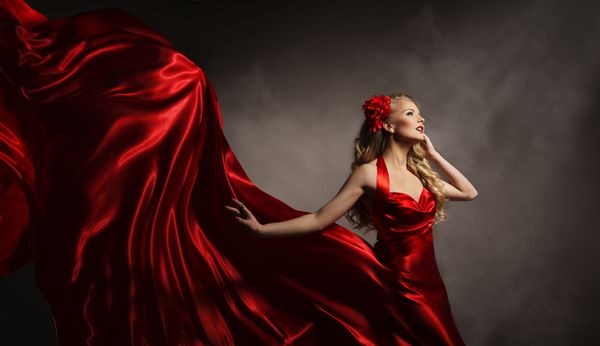 مدل در لباس قرمز زن زرق و برق دار در پرواز پارچه ابریشمی بلند در باد زیبایی مد پرتره