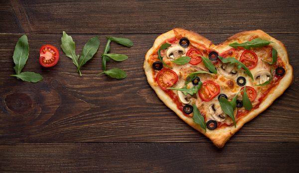 ولنتاین روز پیتزا در شکل قلب با عشق کتیبه در زمینه تاریک روستایی چوبی نمای بالا کپی فضای
