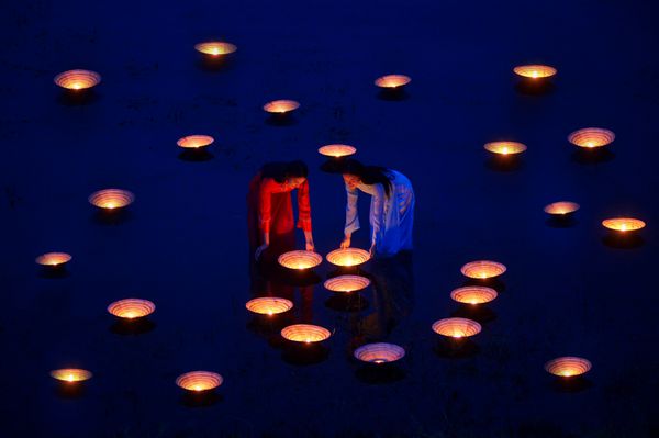زن زیبا با فرهنگ ویتنام لباس سنتی در نور شمع در ساعت آبی پس از غروب آفتاب لباس سنتی سبک پرنعمت ویتنام