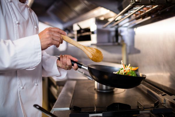 بخش متوسط ​​آشپز آماده غذا در آشپزخانه یک رستوران است