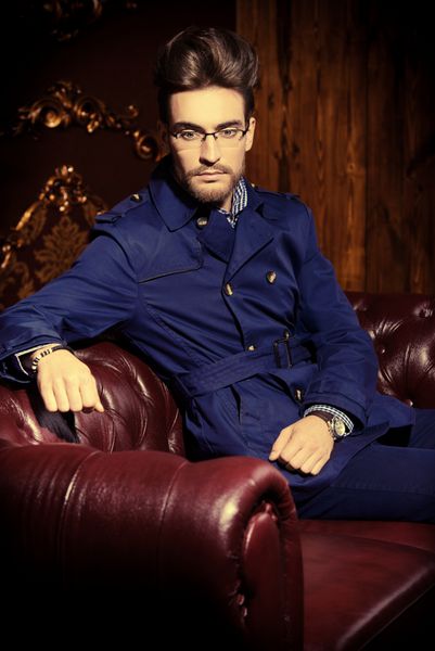 Portrait of a well-dressed imposing man in elegant glasses posing in apartments with luxurious classic interior Men