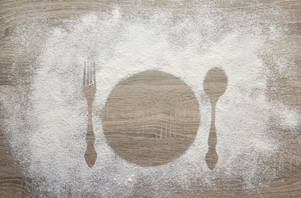چاپ از ظروف چنگال و قاشق در آرد آرد سفید بر روی میز چوبی فضایی برای متن