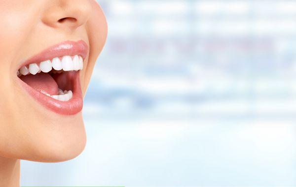 Laughing woman mouth with great teeth over blue background.
