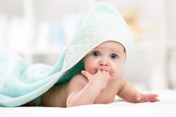 بچه کودک خنده دار زیر یک دستمال مخصوص حوله ای پس از حمام کردن