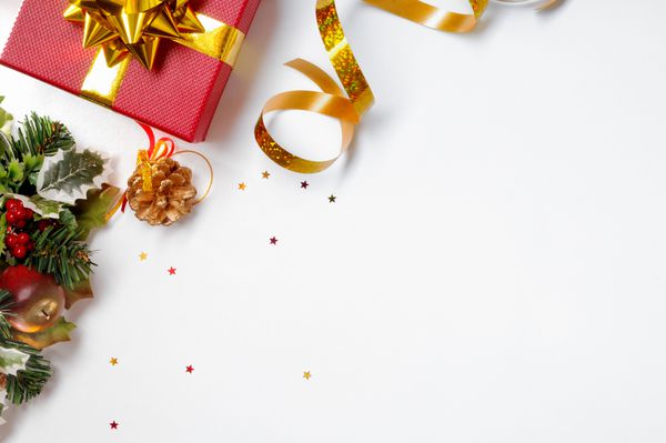 دکوراسیون کریسمس سفید در سمت چپ جعبه قرمز و هدیه و نوار طلایی با تزئین گل نمای بالا ترکیب افقی و مورب