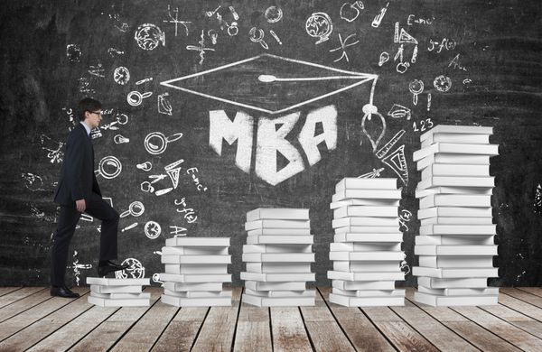 یک مرد با استفاده از پله هایی که از کتاب های سفید ساخته شده اند به کلاه فارغ التحصیلی می رسد کلمه نوشته شده توسط MBA بر روی تخته سیاه سیاه که نماد آموزش و پرورش حرفه ای حرفه ای است