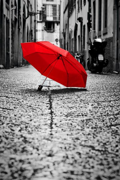 چتر قرمز در خیابان سنگ شکن در شهر قدیمی باد باران آب و هوای طوفانی رنگ سیاه و سفید مفهومی ایده فهرست سبک یکپارچهسازی با سیستمعامل