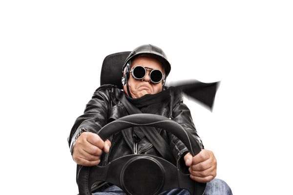 مرد ارشد در کت چرمی سیاه و عینک ایمنی بسیار سریع در صندلی ماشین جدا شده بر روی زمینه سفید نشسته است