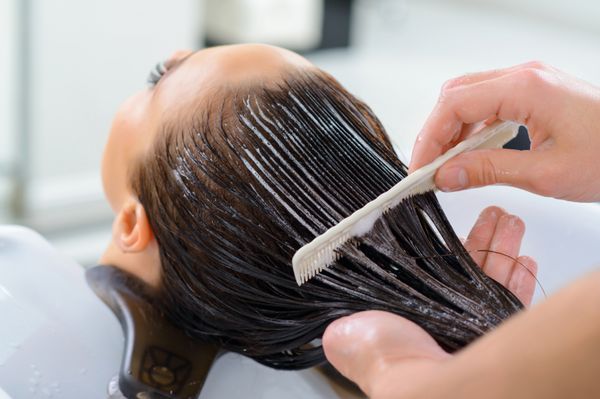 درمان حرفه ای مشتری در حال استراحت است در حالیکه موهایش مراقبت حرفه ای را گرفته است