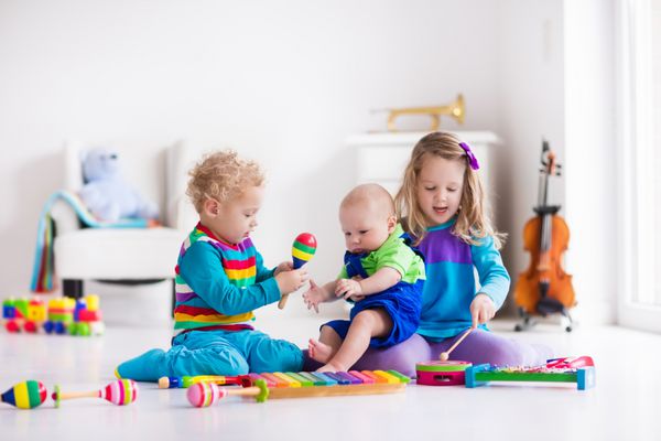 کودکان با ابزار موسیقی آموزش موسیقی برای بچه ها اسباب بازی هنر رنگارنگ دختر کوچک و پسر بازی می کند بچه با زایلوفون گیتار فلوت ویولن توسعه اولیه برای کودک نو پا و کودک