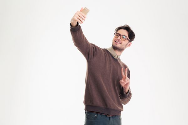 پرتره یک مرد گاه به گاه شاد که عکس های خودمختار بر روی تلفن های هوشمند را جدا می کند در پس زمینه سفید