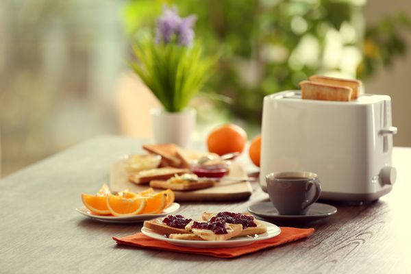 جدول برای صبحانه با نان تست قهوه و میوه در پس زمینه مبهم