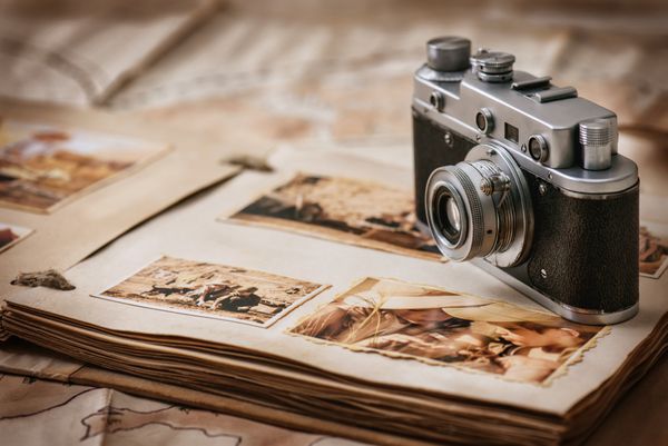 آلبوم عکس با عکس سفر و دوربین قدیمی قدیمی در پس زمینه از نقشه های قدیمی