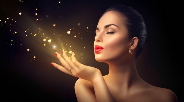 Beauty Young Woman Blowing Magic Dust with golden hearts and stars from her hands Valentine
