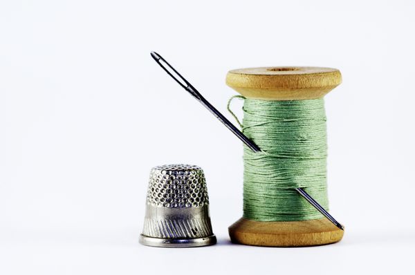 Old spool of thread with needle closeup Tailor
