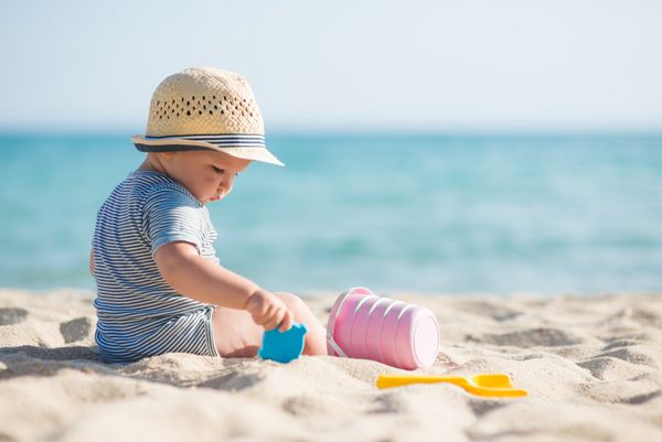 پسر بچه ناز با اسباب بازی های ساحلی
