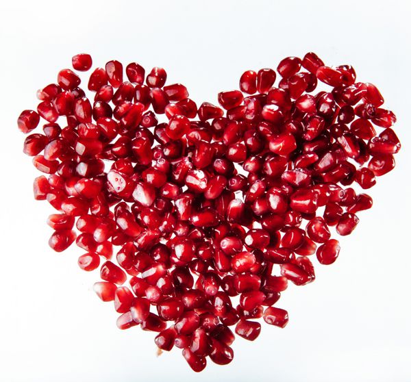 دانه های انار در شکل قلب جدا شده بر روی سفید