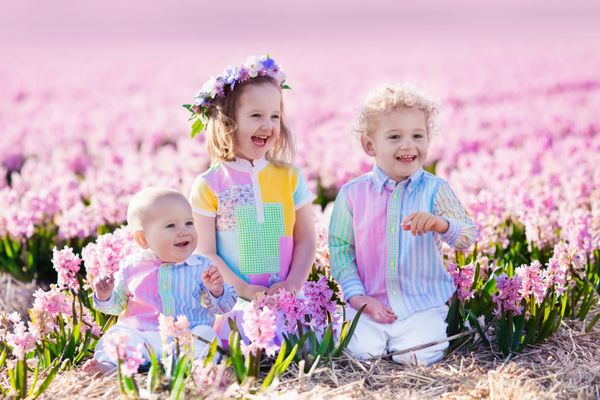 سه بچه در مزرعه گل یاسمن زیبا دختر کوچک کودک نوپا و کودک در باغ تابستان آفتابی با گل های بنفش بازی می کند بچه ها سرگرم کننده در خارج از منزل برادران و خواهر با هم