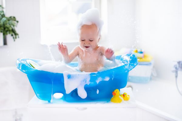 کودک خنده دار مبارک با داشتن حمام با حباب های فوم کودک کوچک در وان حمام بچه ی خندان در حمام با اردک اسباب بازی رنگارنگ شستن نوزاد و حمام کردن بهداشت و مراقبت از کودکان جوان