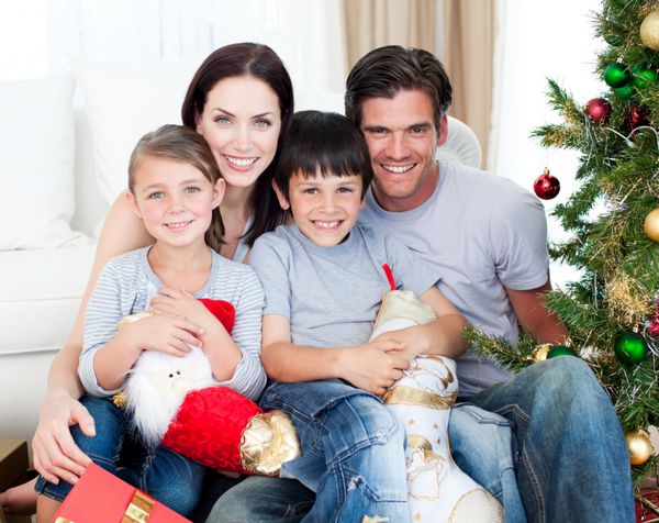 پرتره یک خانواده خندان در زمان کریسمس با داشتن هدایای زیادی در منزل