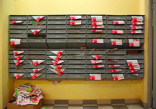 صندوق های پستی در سالن ورودی یک خانه مسکونی پر از آگهی های کاغذی با کتیبه در زبان روسی قرمز و سفید شهر Balashikha روسیه