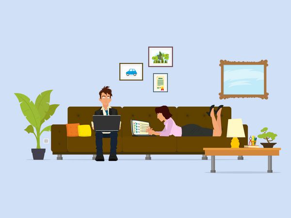 زن و شوهر جوان در حال کار بر روی یک لپ تاپ در حال نشستن و دروغ گفتن روی مبل در اتاق نشیمن بردار یک مرد و یک زن در اینترنت از خانه کار می کنند