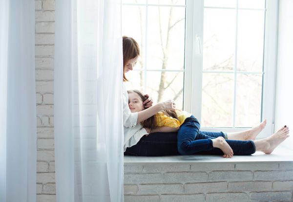 دوست داشتنی زن با کودکش نشسته روی یک پنجره