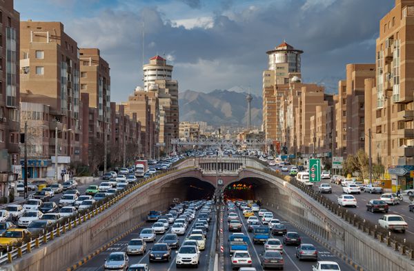 تهران ایران 19 فوریه 2016 بارگذاری ترافیک سنگین در و در اطراف تونل توحید با برج میلاد و کوه های البرز در پیشینه توحید سومین بلندترین تونل شهری در خاورمیانه است