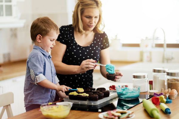 کودک زیبا و مادر پخت در آشپزخانه با عشق