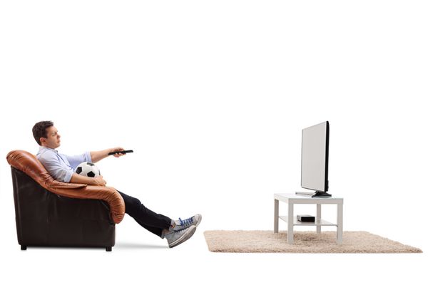 پسر جوان خسته از تماشای فوتبال در تلویزیون و تغییر کانال جدا شده بر روی زمینه سفید