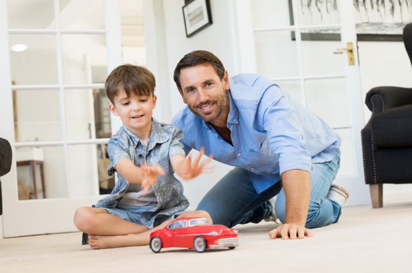 پدر با پسر کوچک با ماشین اسباب بازی پدر و پسر خندان با هم در اتاق نشیمن پدر وقت کافی با پسر در خانه دارد