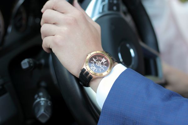 بازرگان رانندگی ماشین خود را دست در فرمان دست با ساعتهای طلایی مفهوم کسب و کار