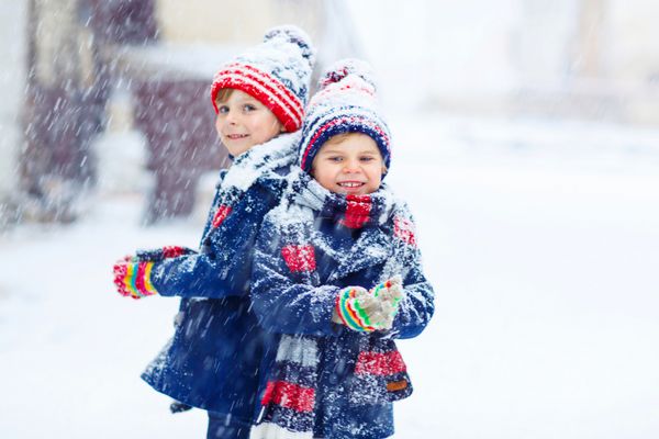 دو بچه بچه کوچک در لباس های رنگارنگ خارج از منزل در طول بارش برف اوقات فراغت در خارج از منزل با کودکان در زمستان در روزهای برفی سرد خواهر و برادر مبارک لذت بردن با برف