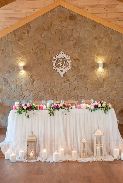 پرزیدنت عروسی شیک نامهای مجرد عروس جدید بر روی دیوار گل های تازه بر روی میز شمع های سوختن بر روی زمین