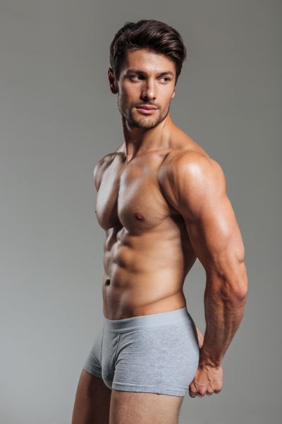 مرد جوان نشان دادن عضلات جدا شده در پس زمینه خاکستری