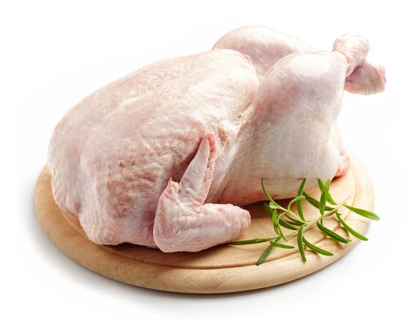 مرغ کامل خام بر روی تخته چوبی برش جدا شده بر روی زمینه سفید