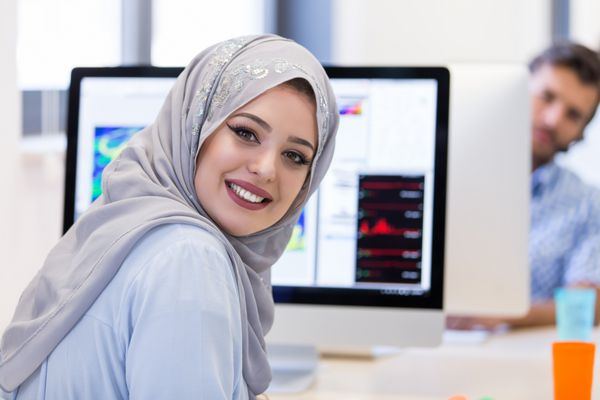 زن جوان کسب و کار عربی با پوشاندن حجاب در حال کار در اداره راه اندازی خود است