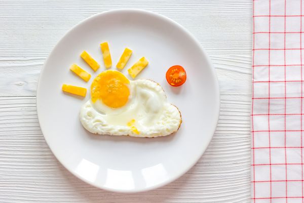 صبحانه تخم مرغ سرخ شده در تابستان برای بچه در زمینه های چوبی