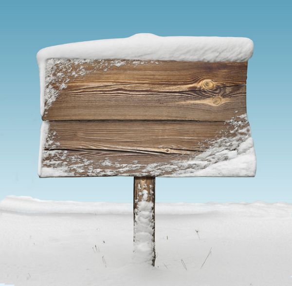 نشانه چوبی با برف در آن و آسمان آبی در پس زمینه