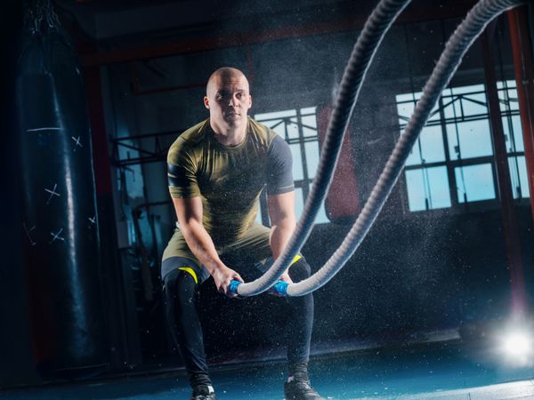 مردان با نبرد طناب جنگ در ورزشگاه تناسب اندام CrossFit