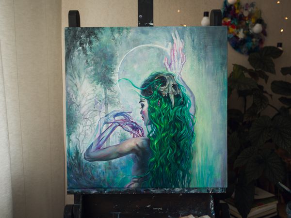 نقاشی Surreal یک زن با جمجمه گربه در موهای سبز بر روی صحنه سیاه در استودیوی هنرمند
