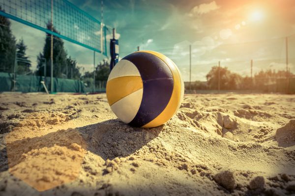 والیبال ساحلی توپ بازی تحت نور خورشید و آسمان آبی