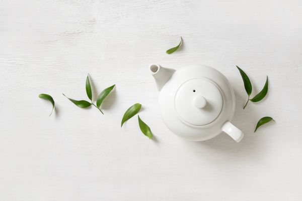 مفهوم چای قوری با چای با برگ چای سبز از بالا دیده می شود