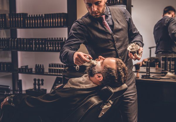 Barber applies shaving foam to a man